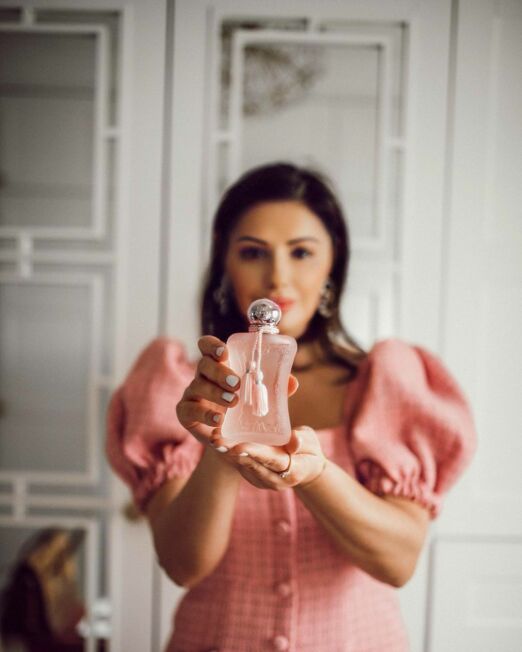 Vrouw houd Parfums de Marly Delina La rosee parfumfles vast in haar handen