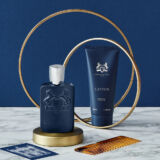 blauwe parfumfles en blauwe tube op een gouden display van parfums de marly persival